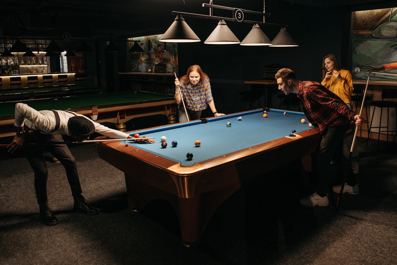 Group of friends enjoying a game of billiards indoors, capturing fun and leisure moments.